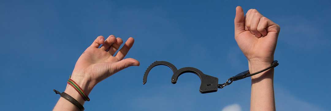 Hands freed from handcuffs against a blue sky.