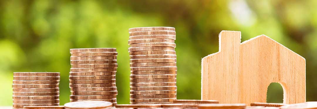 A house beside a stack of coins to illustrate an unwritten mortgage.