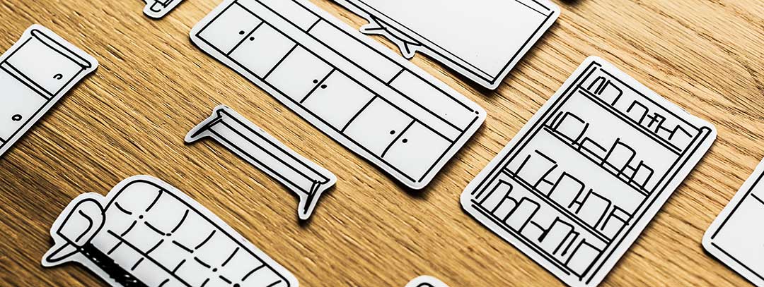 Paper cut outs of furniture and personal effect laid out on a wooden desk to show property to be distributed before probate.