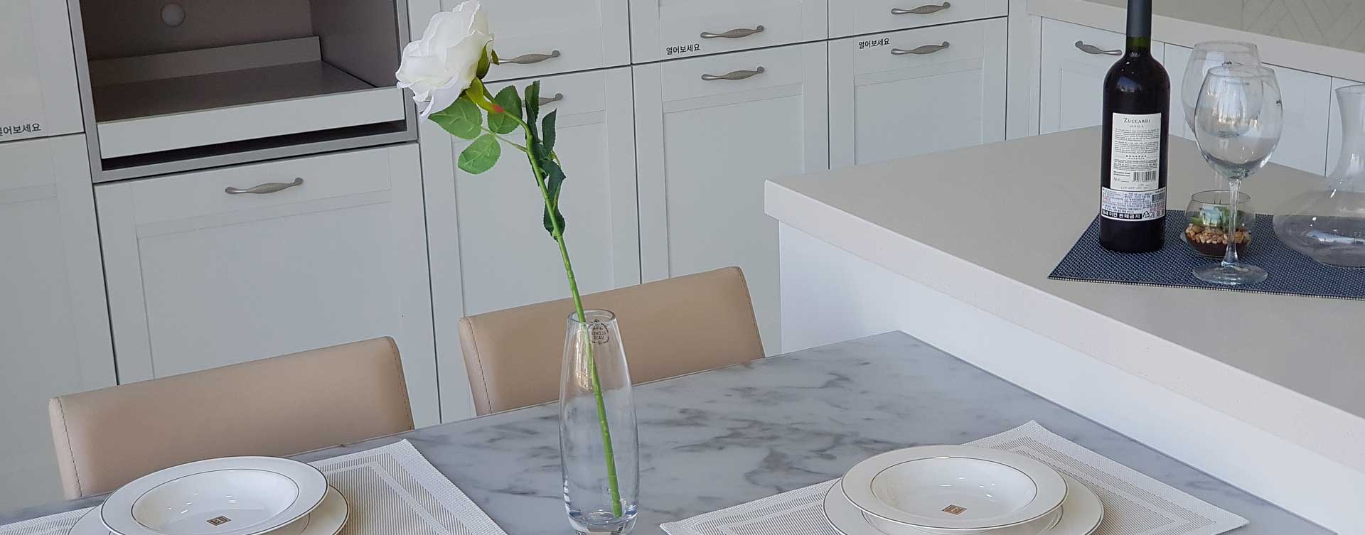 A table in a white kitchen with place settings for two, a wine bottle and a white rose in a vase, indicating a reconciliation between separated Spouses. Can the Marital Property Regime be revived after a Judicial Separation of Property?
