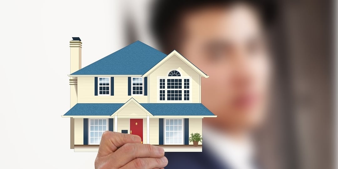 A guy holding a model house