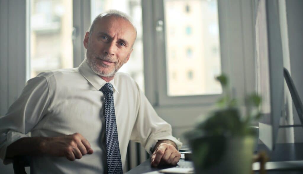 An older man sitting at a table writing his Last Will and Testament