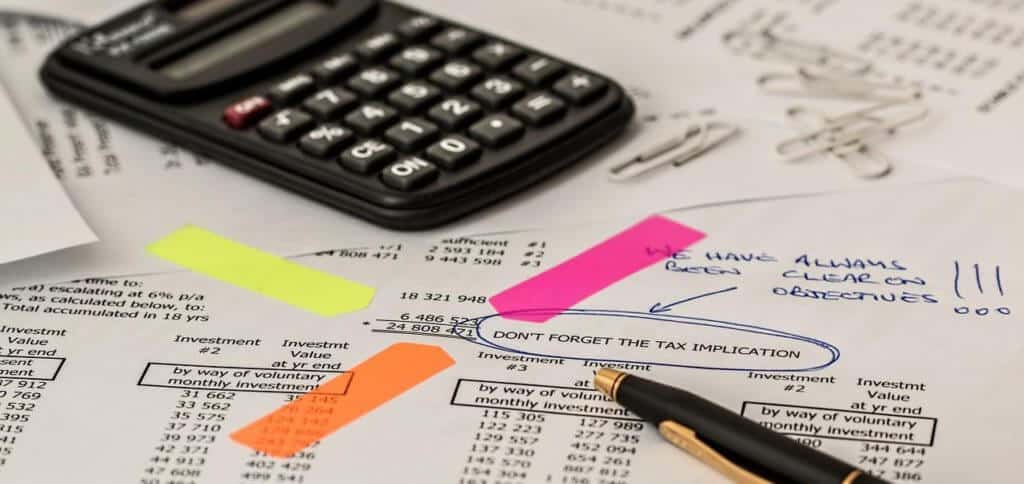 A calculator and tax papers symbolizing computations of a substituted basis for tax free exchange of stock.