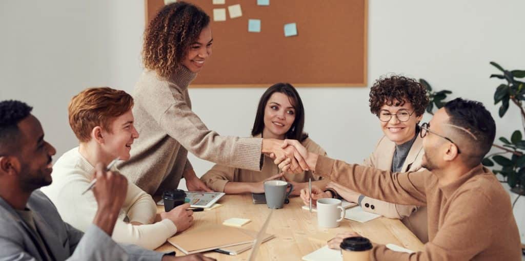 Two people handshaking during a meeting symbolizing a successful Tax Free Exchange transaction.