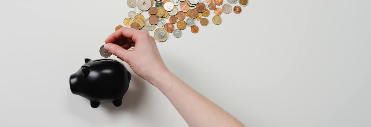A hand inserting coings in a piggy bank symbolizing TITF.
