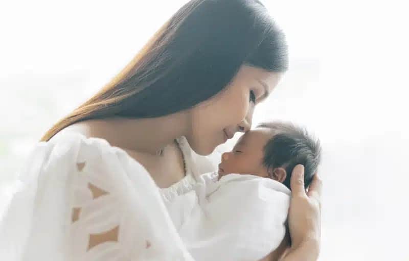 Panoramic banner image of beautiful young Asian mother kissing and hugging newborn baby. Beautiful Family. Maternity concept. Parenthood. Motherhood, adoption concept