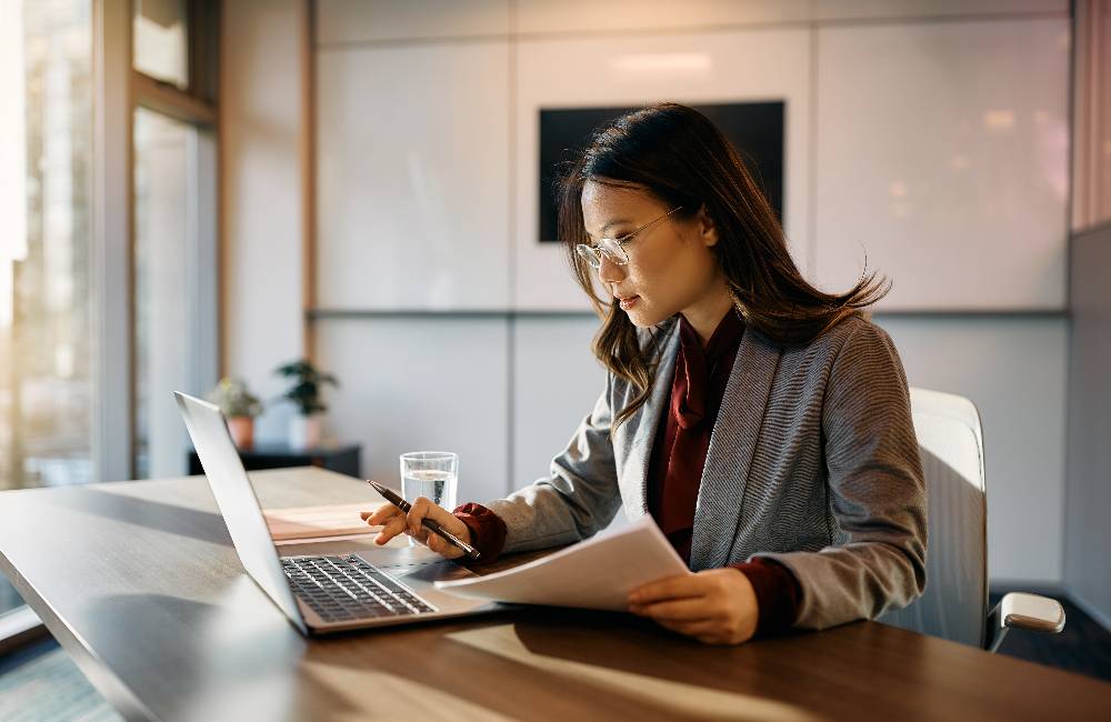 A lady examining documents as part of a Representative Agent's tasks is to receive summons on behalf of the Branch Office