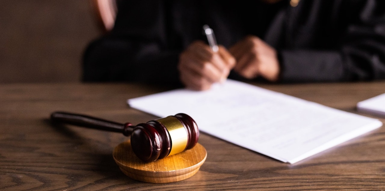 A judge writing on his desk beside a gavel