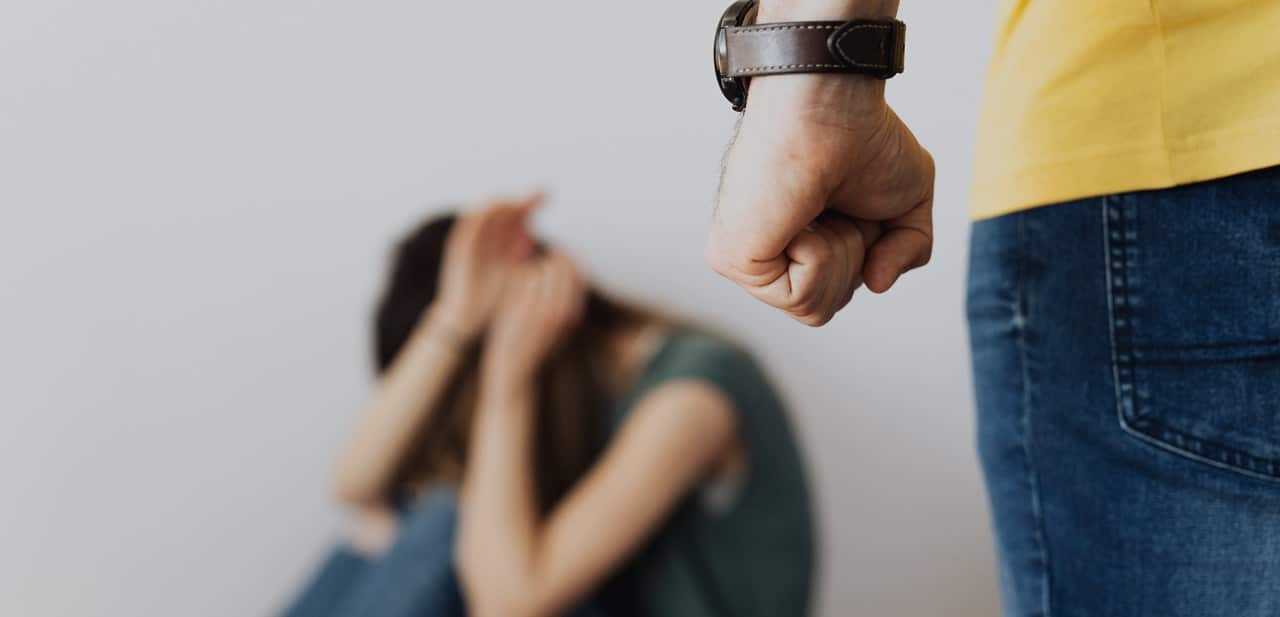 A man with his fist closed and a scared woman at the background