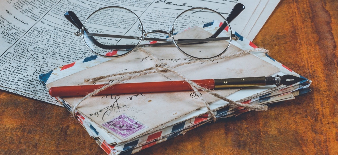 A bundle of mail with a reading glasses on top