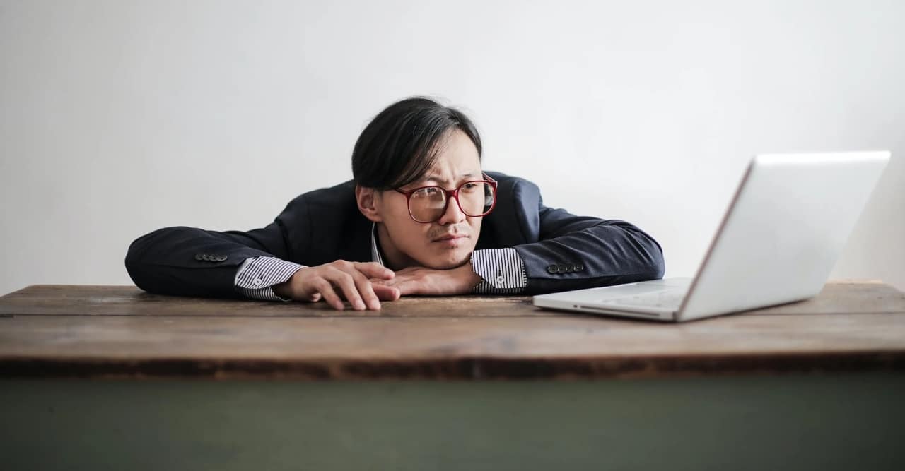 A man looking at his laptop while slacking off the table.