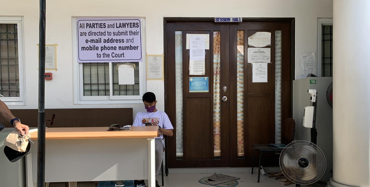 A man sitting in front of a Hall of Justice receiving window
